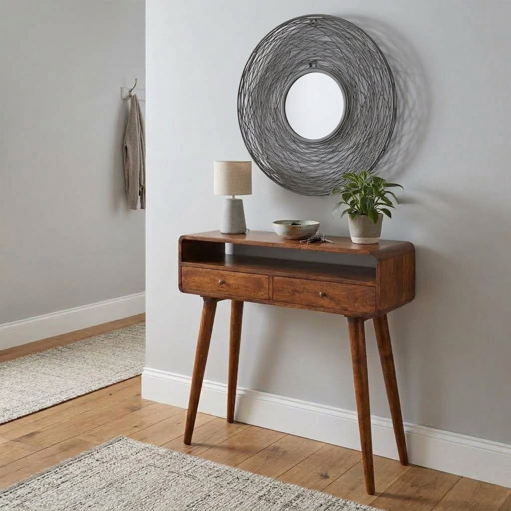 Round grey nest frame mirror above a curved chestnut console in a hallway